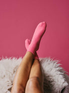 Person wearing pink socks with a pink background