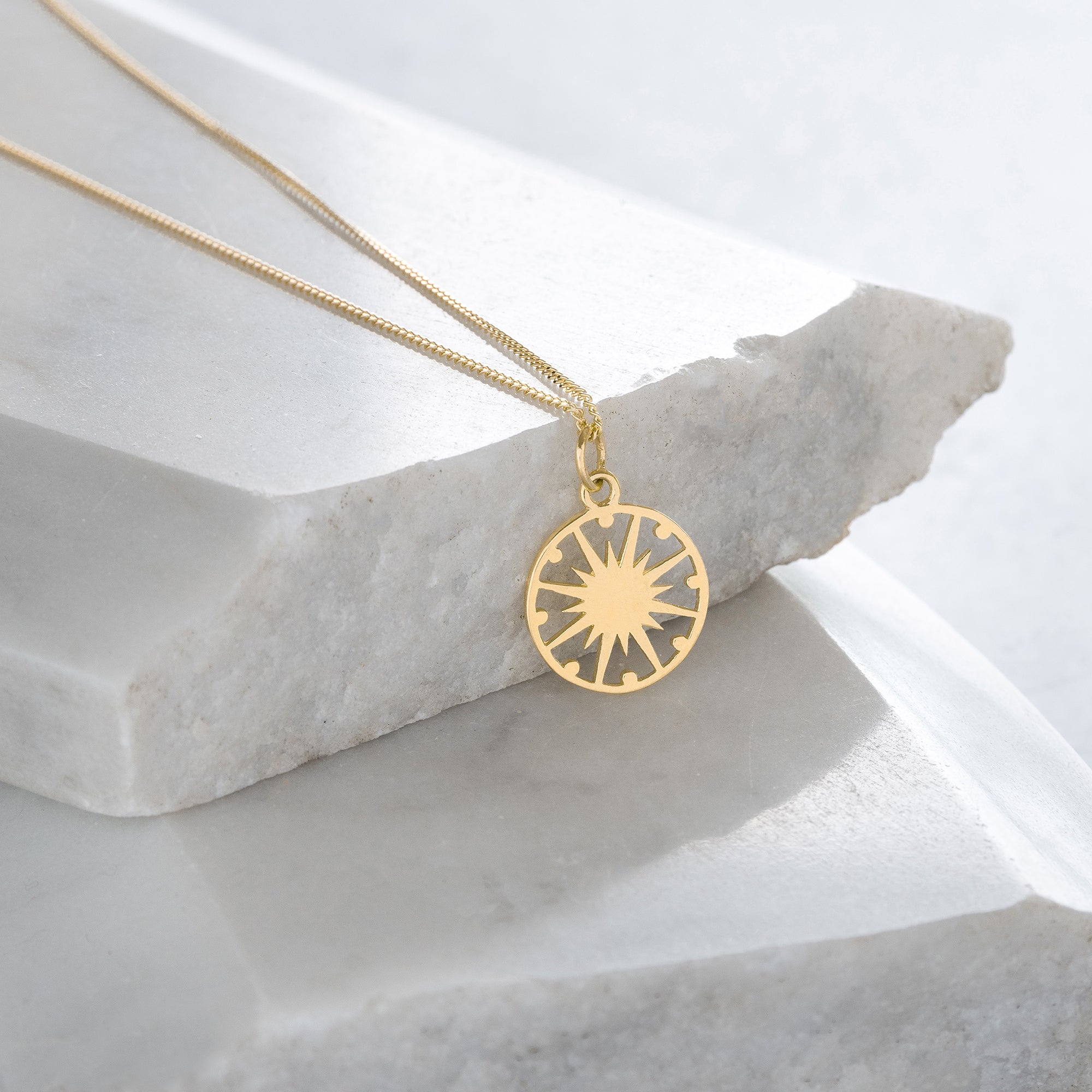 gold vermeil supernova token necklace on marble