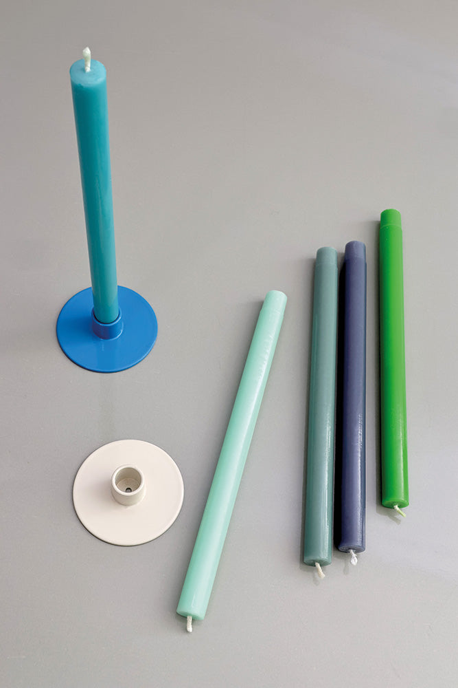 Set of colorful candles and candle holders on a gray background