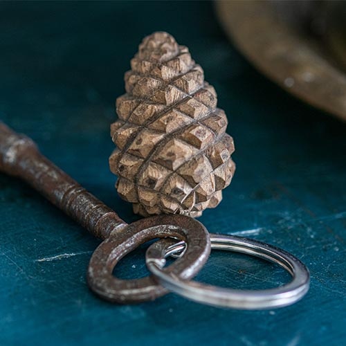 Decorative keychain with textured cone and vintage-style key on a blue surface