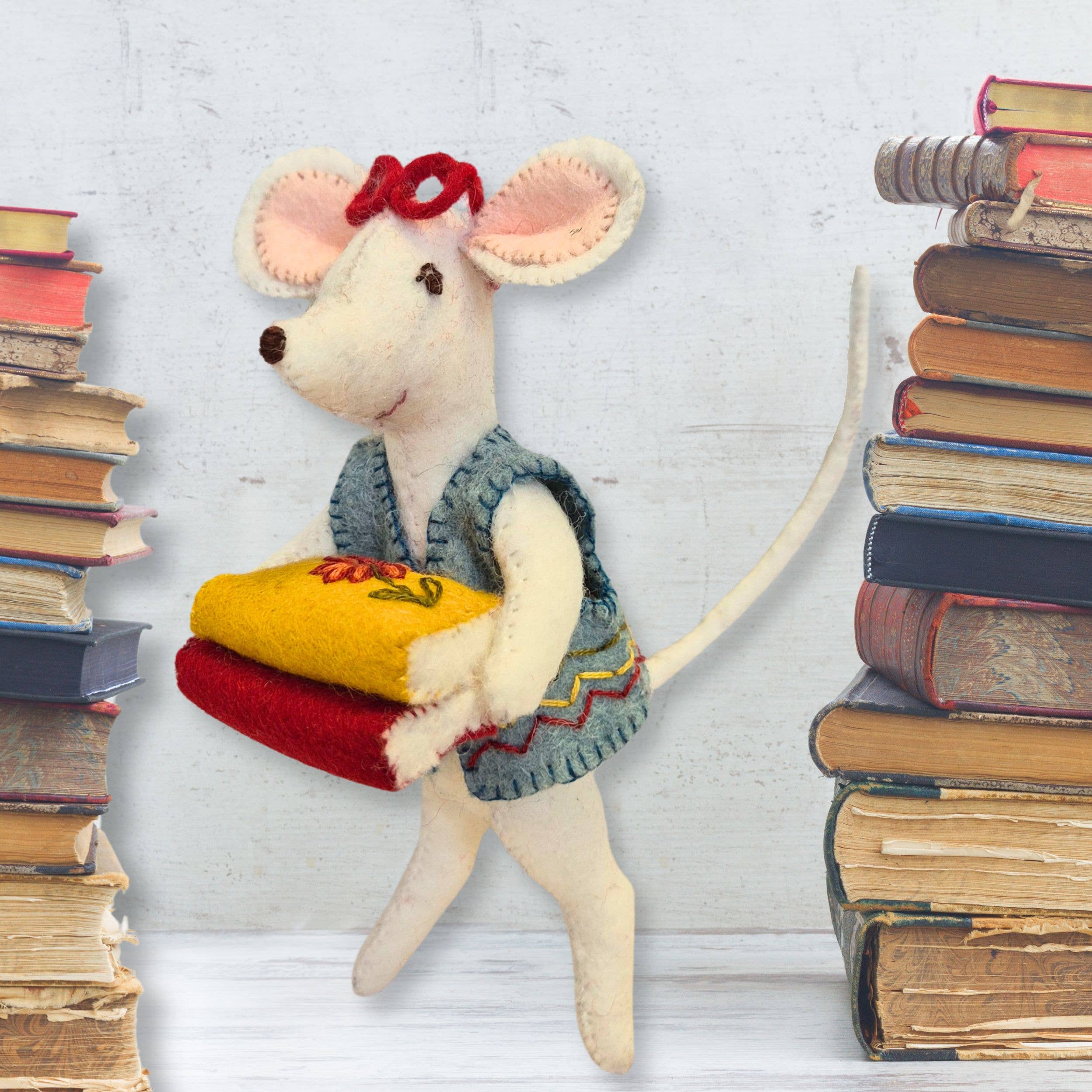 Stuffed mouse toy holding books with stacks of books on a light gray background