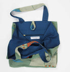 Blue and green tote bag with floral patterns on a white background