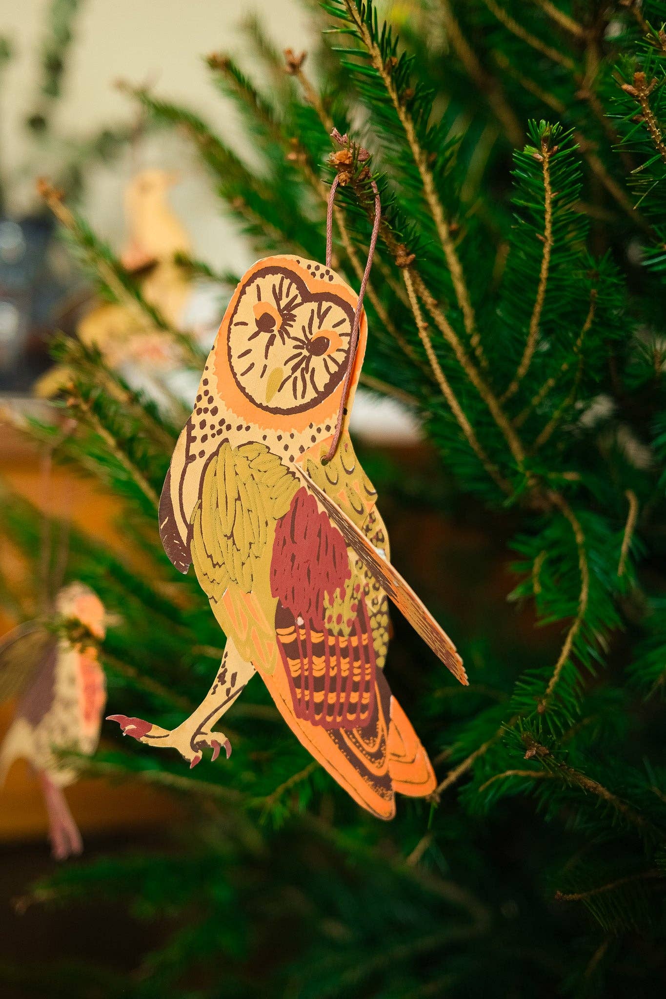 Decorative owl ornament hanging on a Christmas tree