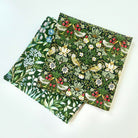Two green fabric hankies with a floral and bird pattern on a white background
