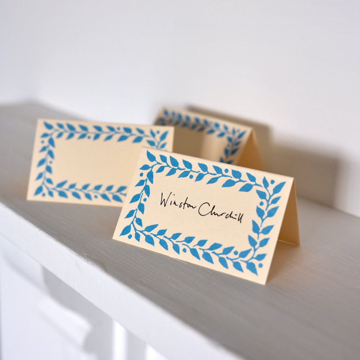 Place cards with blue leaf design on a white surface