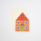 Showing the concertina card folded flat to fit in the envelope. This image shows an illustrated red brick house. 