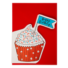 A birthday card featuring a stylized cupcake illustration with white frosting, multicolored sprinkles, a red polka-dot wrapper, and a small blue flag topper that reads 'Happy Birthday' in black script, set against a solid red envelope.