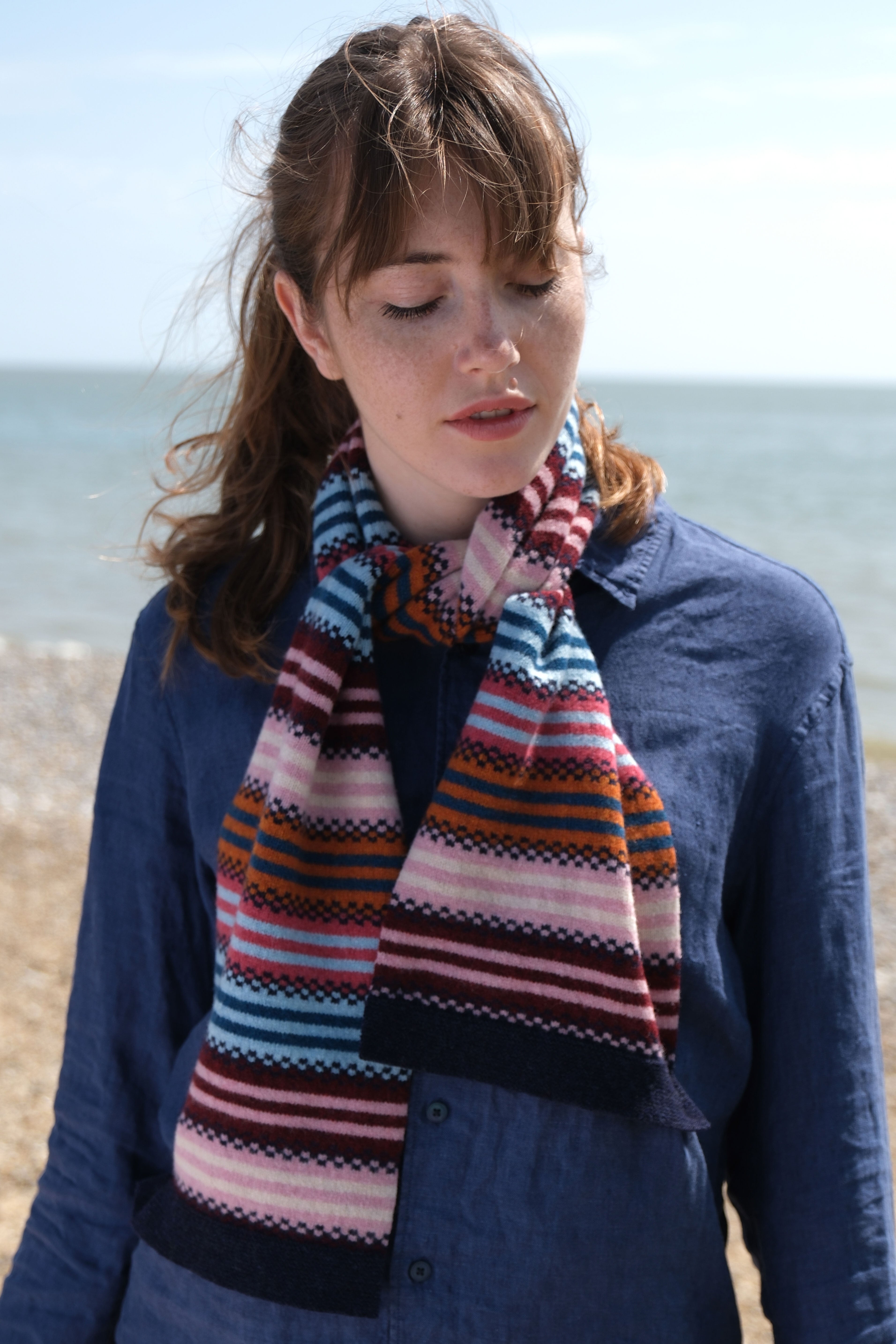 Woman wearing a colorful striped scarf on a beach