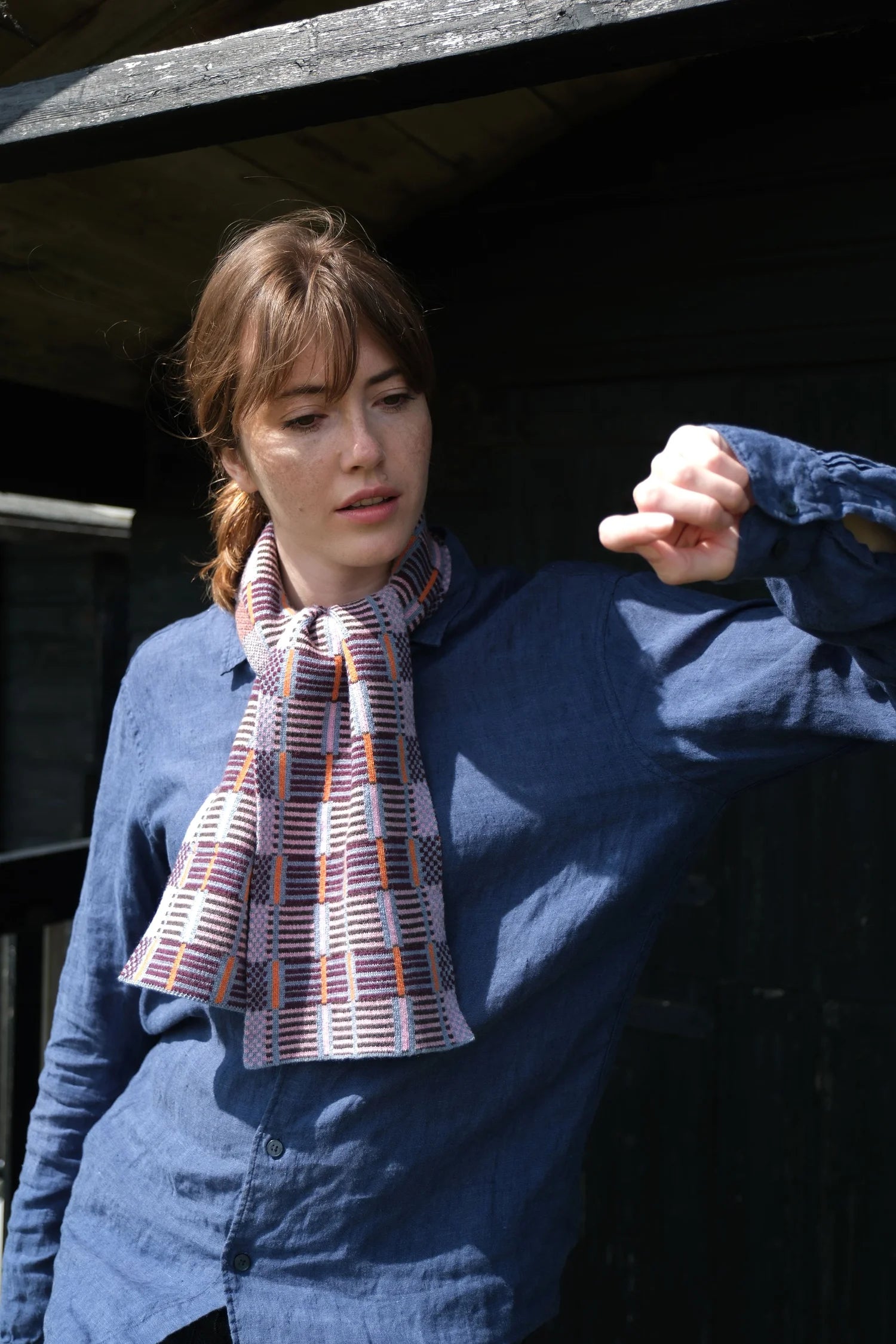 Person wearing a blue sweater and plaid scarf outdoors