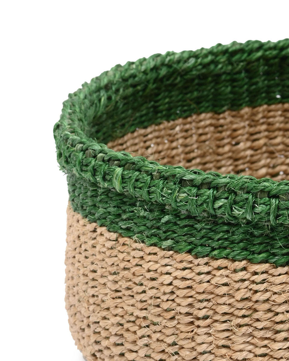 Close-up of a woven basket with green top and brown bottom on a white background
