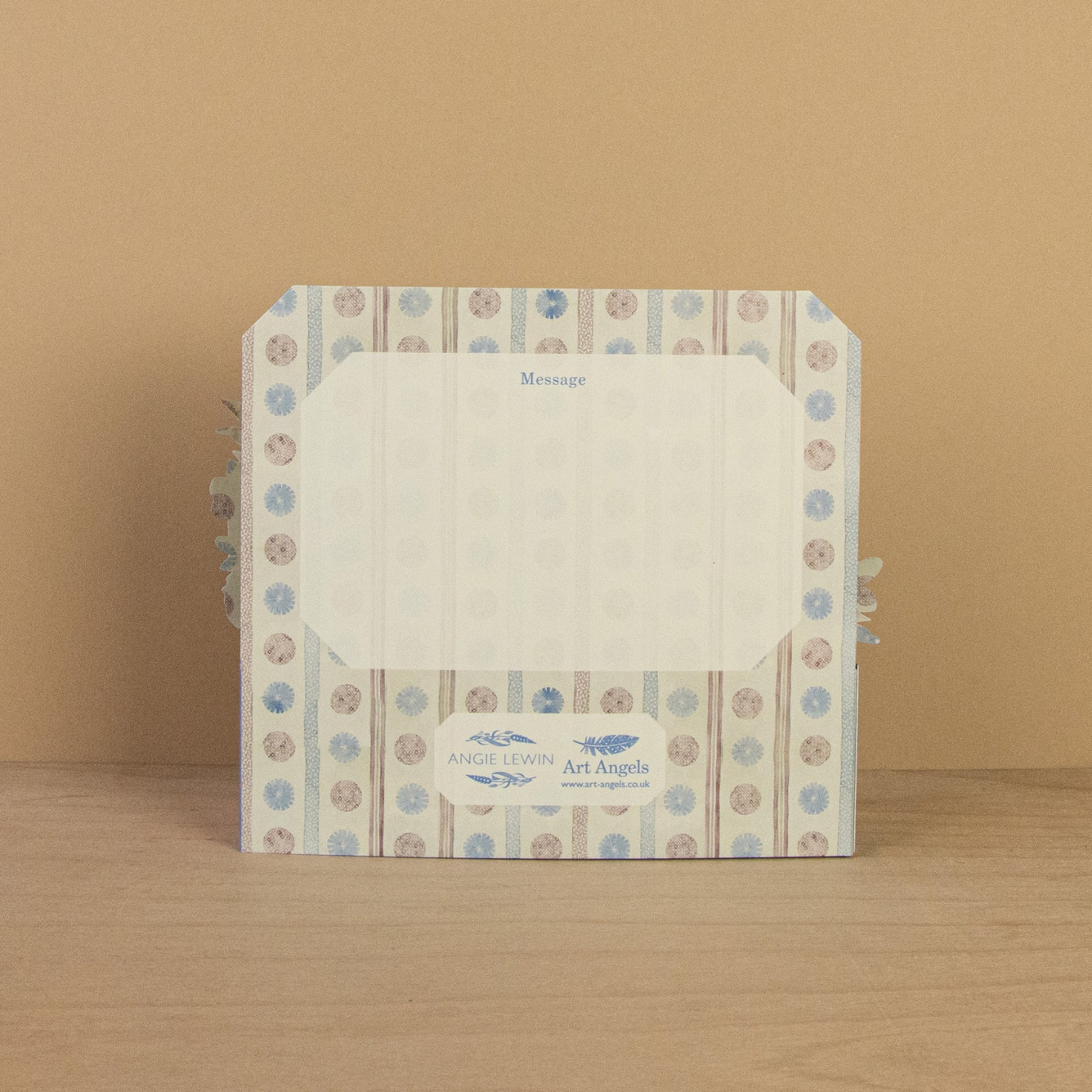 Card with floral design on a wooden surface and beige background