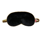 A black velvet sleep mask with gold trim and an elastic gold strap, shown against a plain white background.