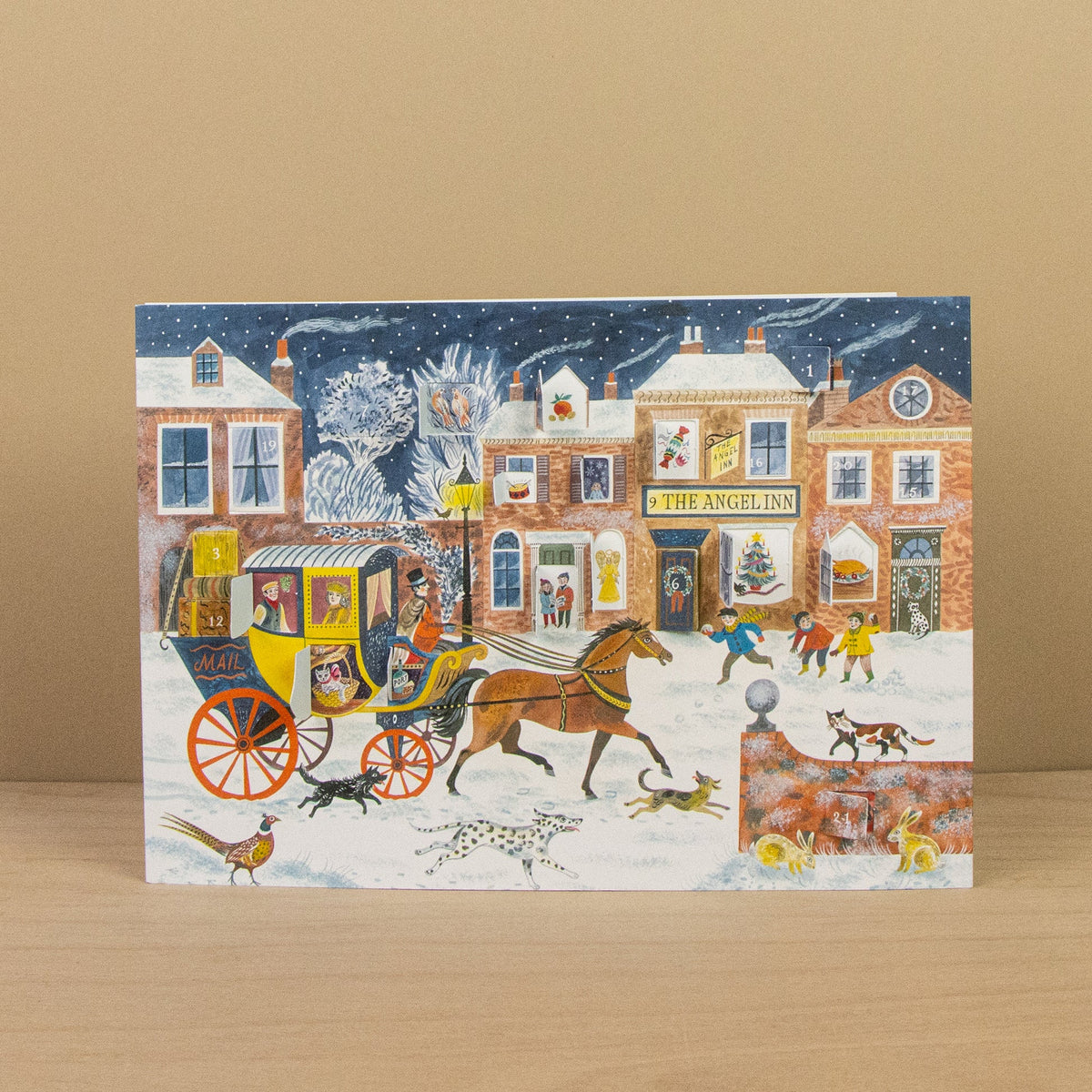 Illustrated Christmas card with a horse-drawn carriage and people in front of 'The Angel Inn' on a snowy street.