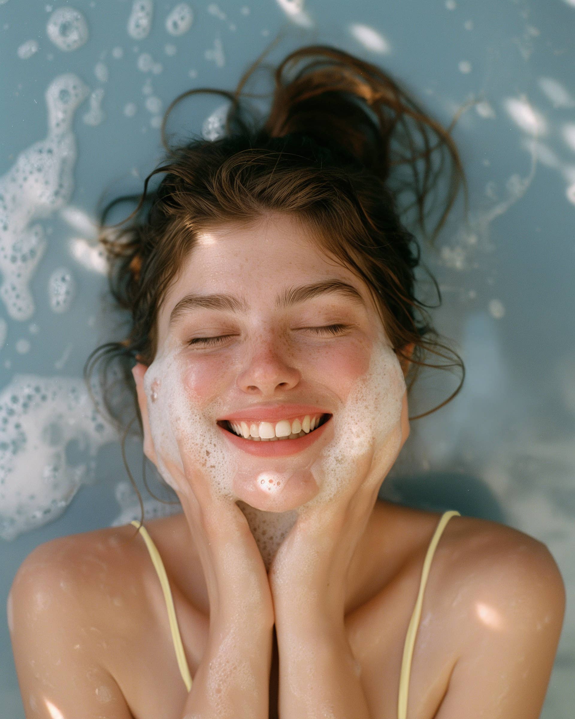 Woman with soap suds on her face against a blue background