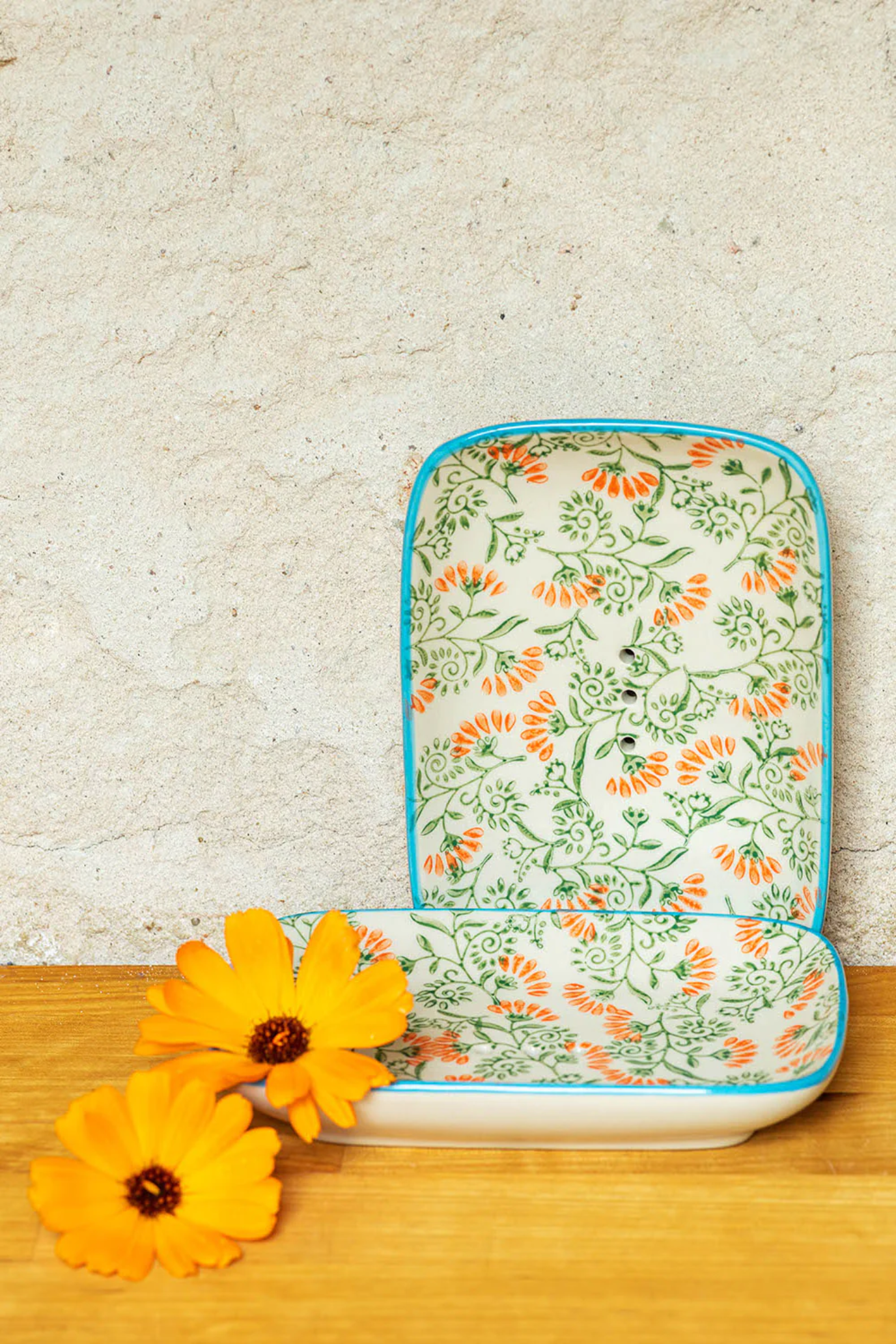 Floral-patterned soap dish on a wooden surface with yellow flowers.
