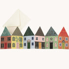 A greetings card with 6 uniquely designed and colourful houses shown with an off-white envelope.