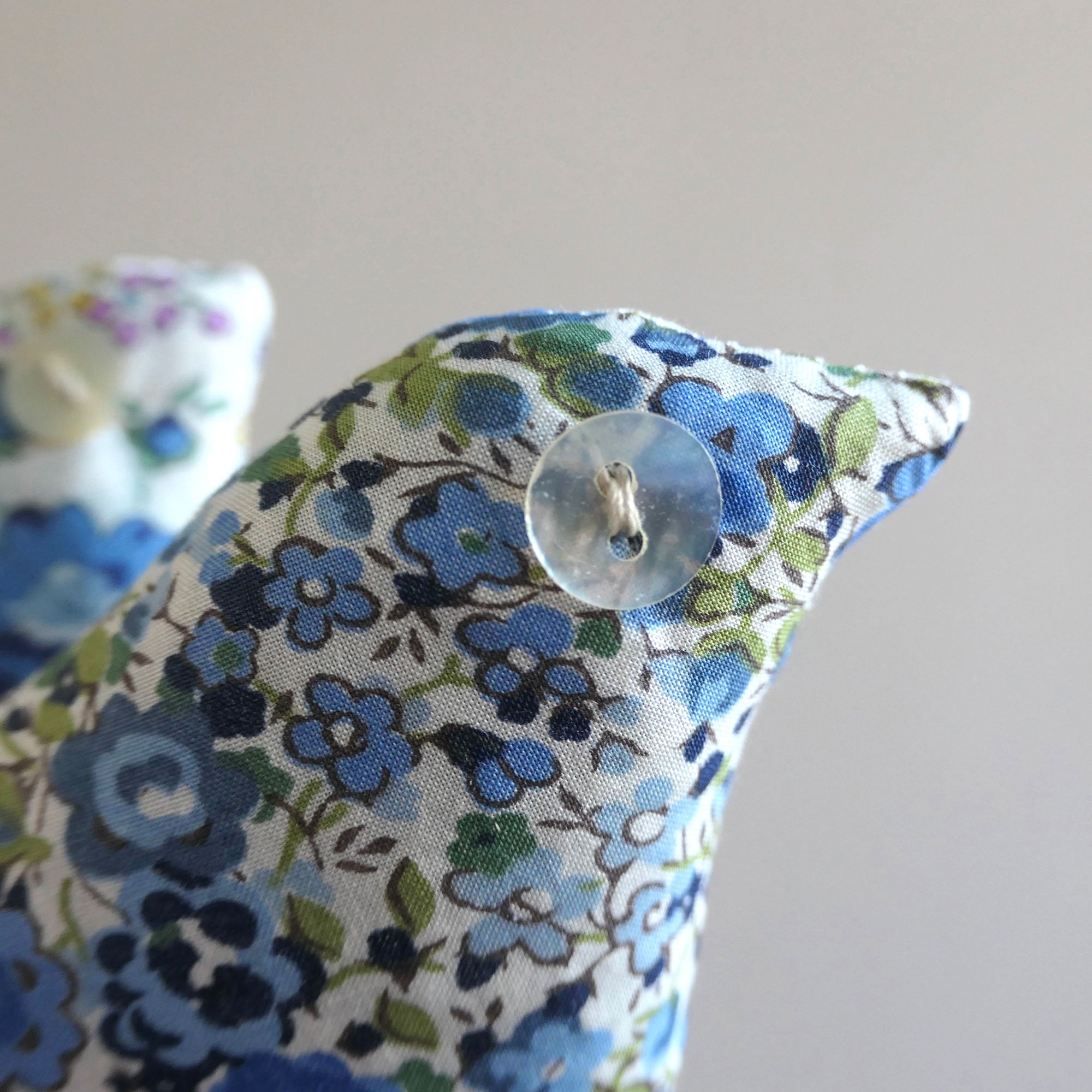 Blue floral fabric bird with floral pattern on a plain background