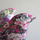 Floral fabric bird-shaped lavender sachet with a button on a light grey background
