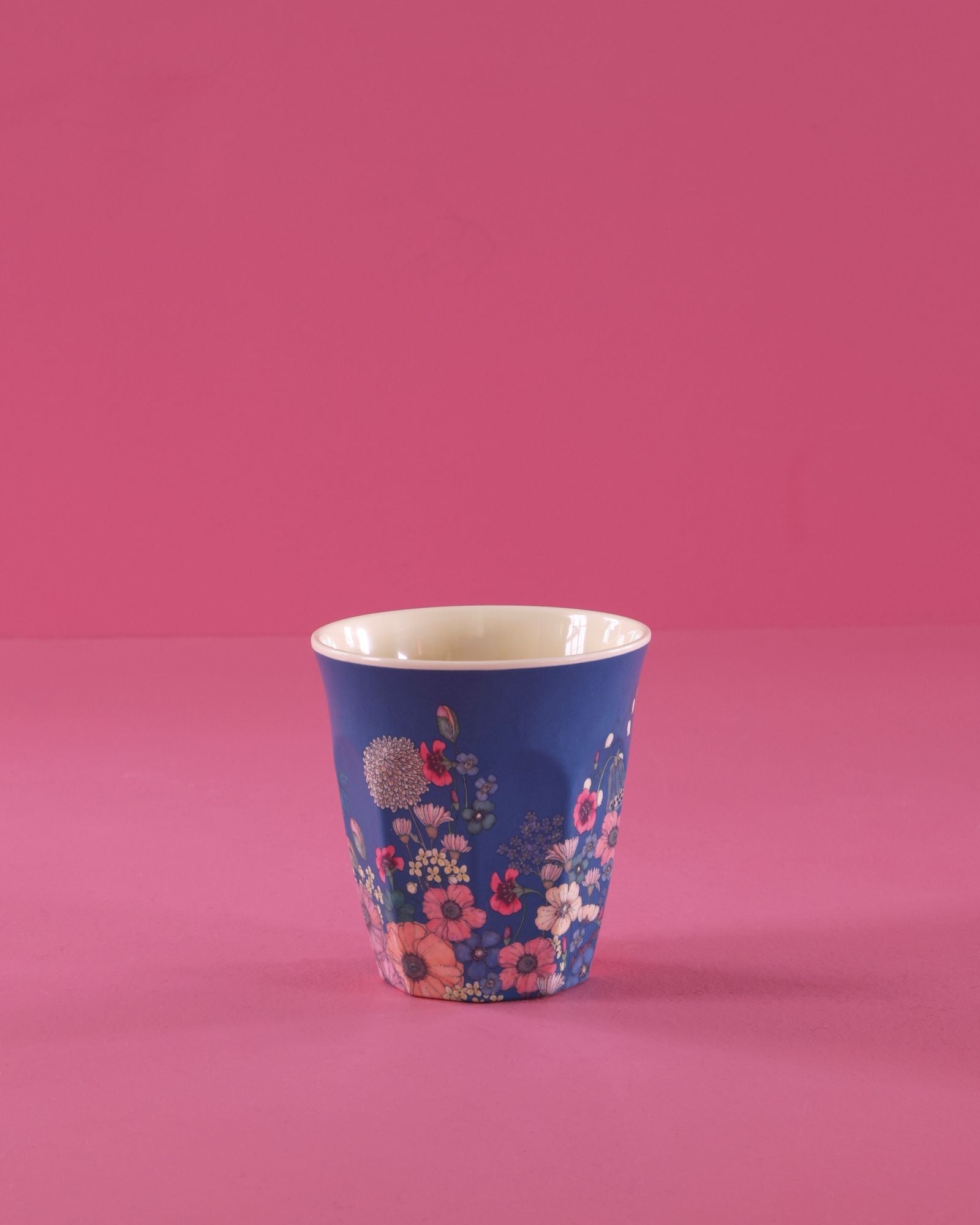 Blue cup with floral pattern on a pink background
