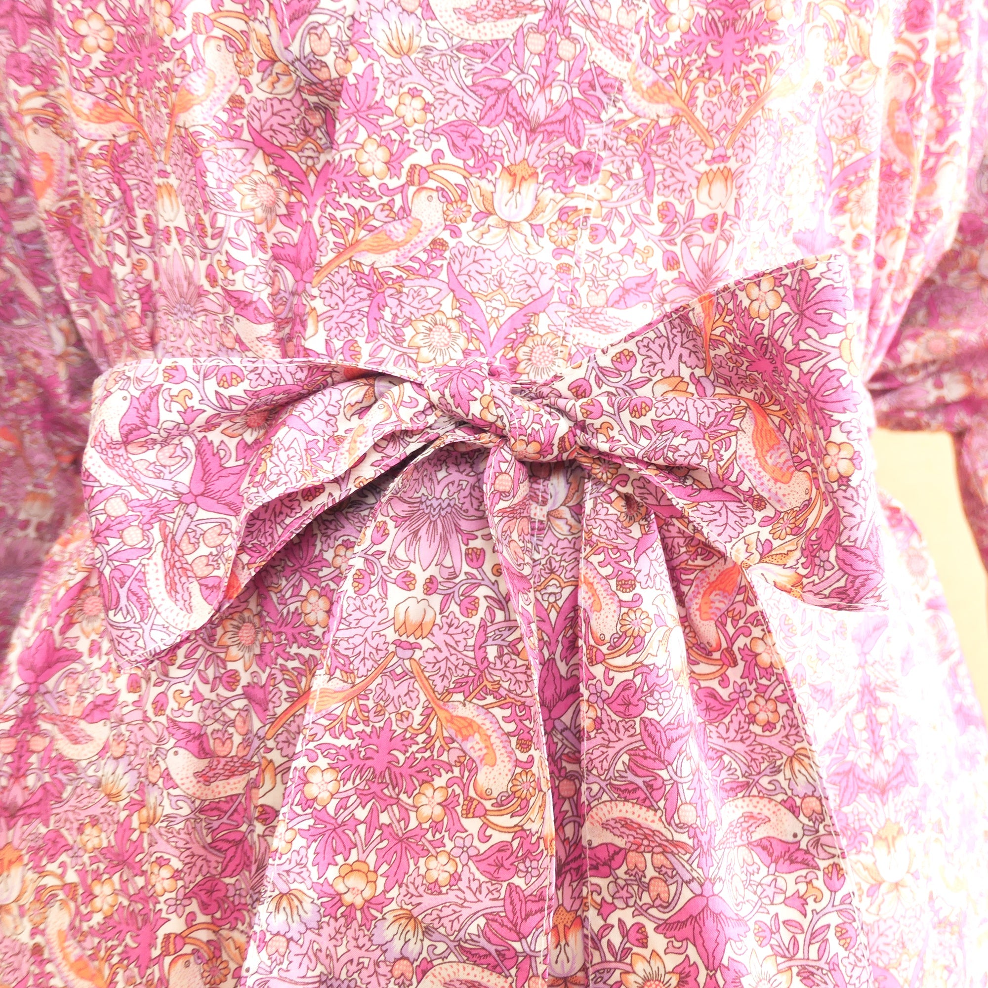 Close-up of a pink Strawberry Thief kimono robe sash with a large bow detail.