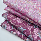 Stack of floral fabric with pink and purple tones on a white background