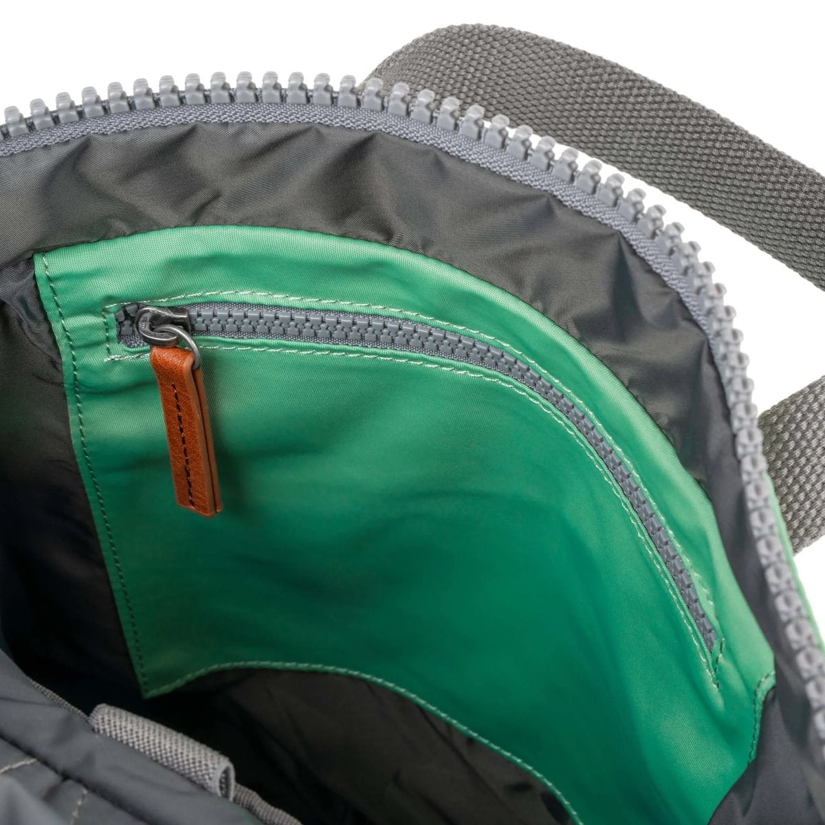 Close-up of a green zipper pocket on a backpack with a white background