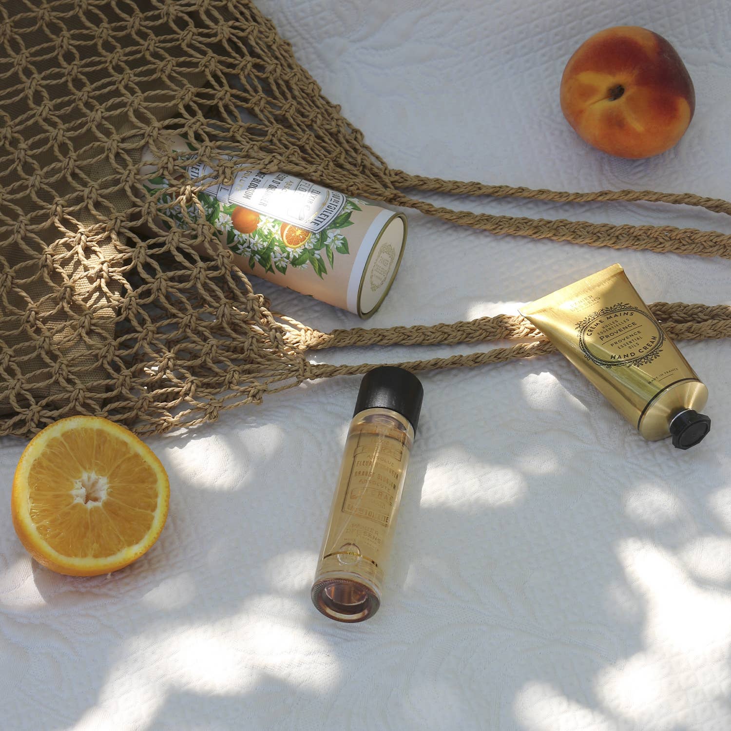 Cosmetic products including a tube, bottle, and peach on a textured surface