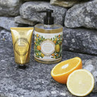 Hand cream and bottle with lemon and orange design on a stone surface