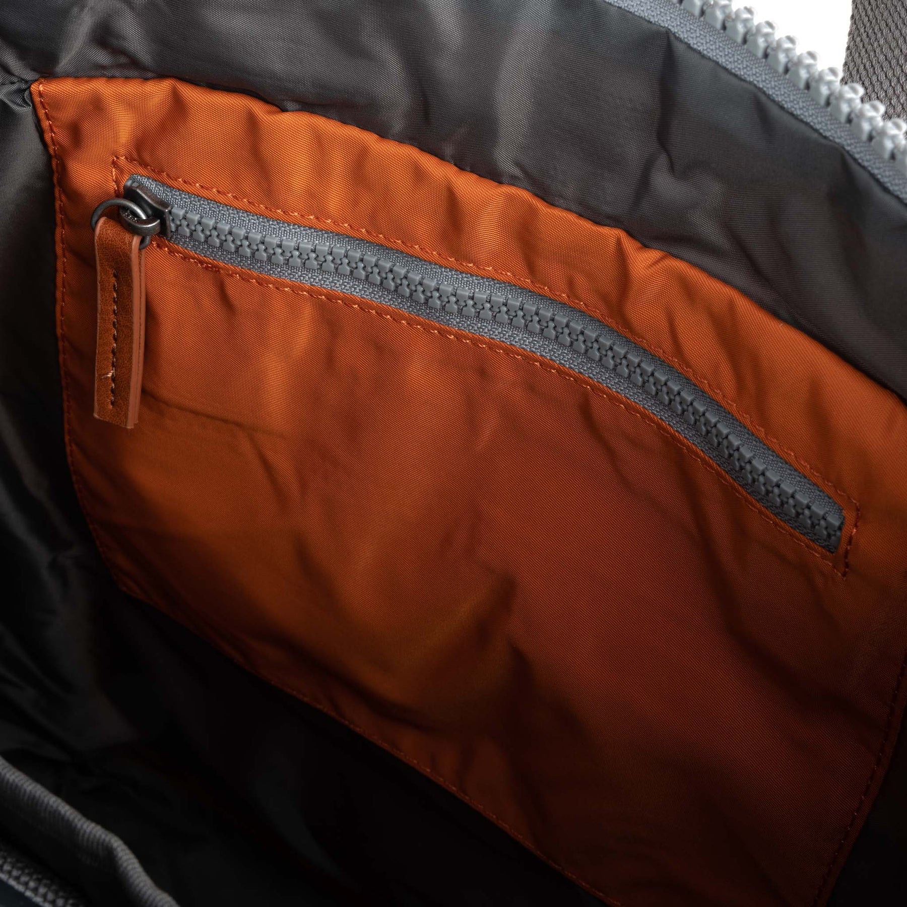 Close-up of a zipper on an orange and black fabric surface
