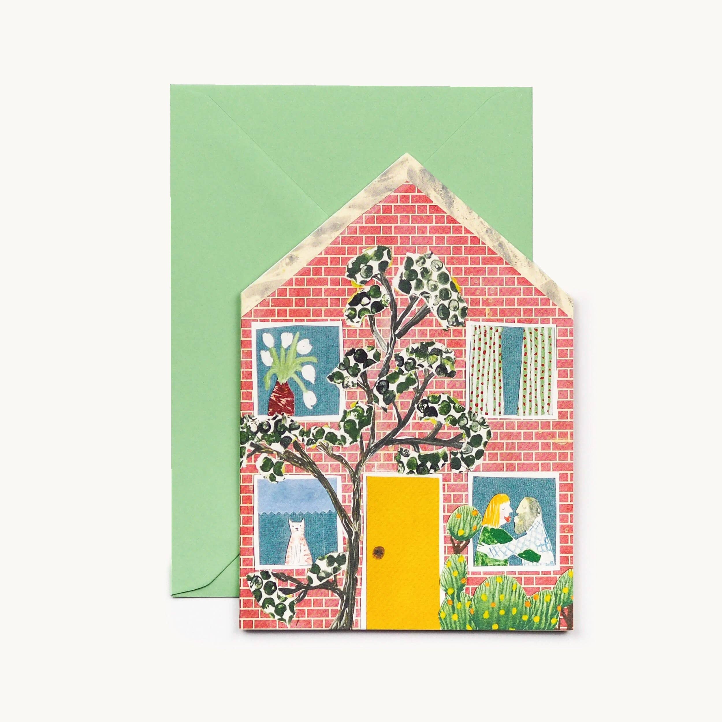 Greeting card with a house design featuring a yellow door and garden scene with a green envelope
