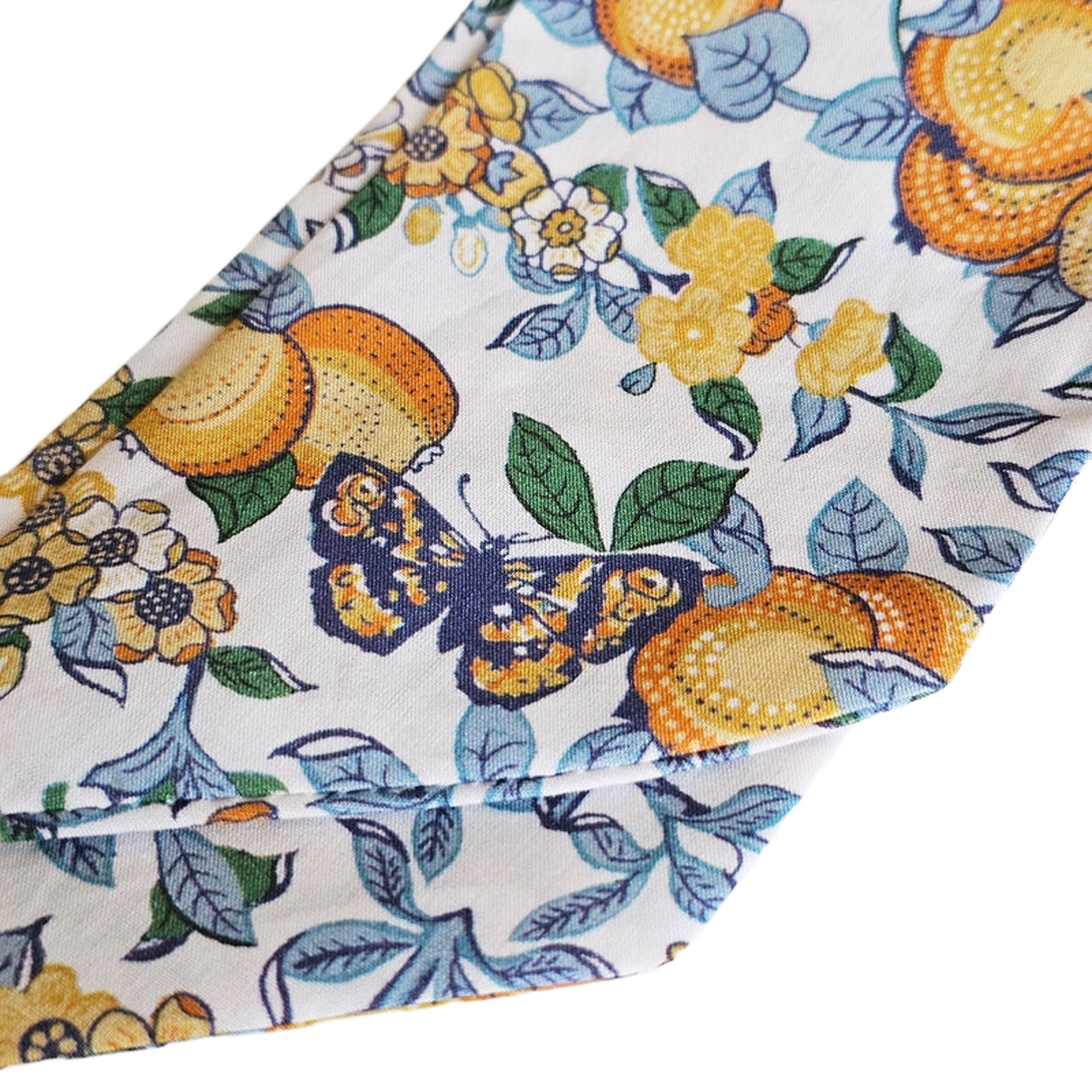 Fabric with a colourful pattern of butterflies, flowers, and fruits on a white background