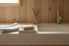 Bar of soap on a stone surface with a wooden wall and faucet in the background