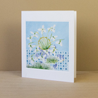 Greeting card with floral design placed on a wooden surface with a beige background behind