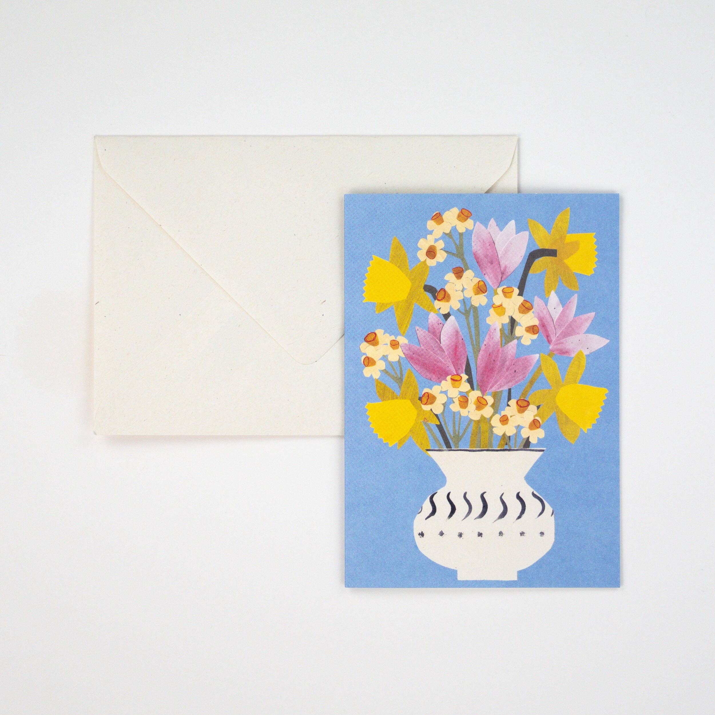 Greeting card with floral design on a blue background, featuring a white envelope.