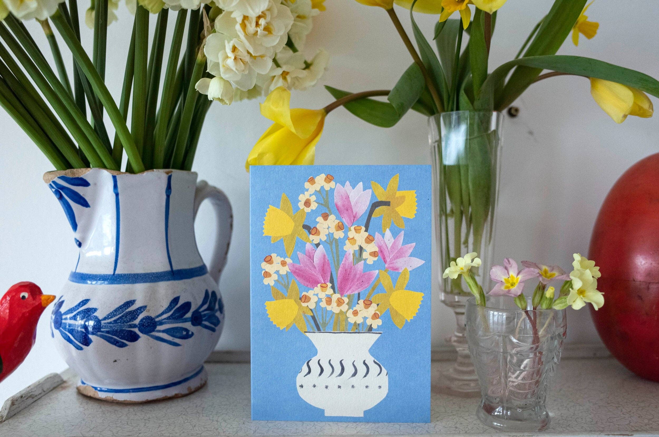 Vases with flowers and a card featuring floral design on a light background