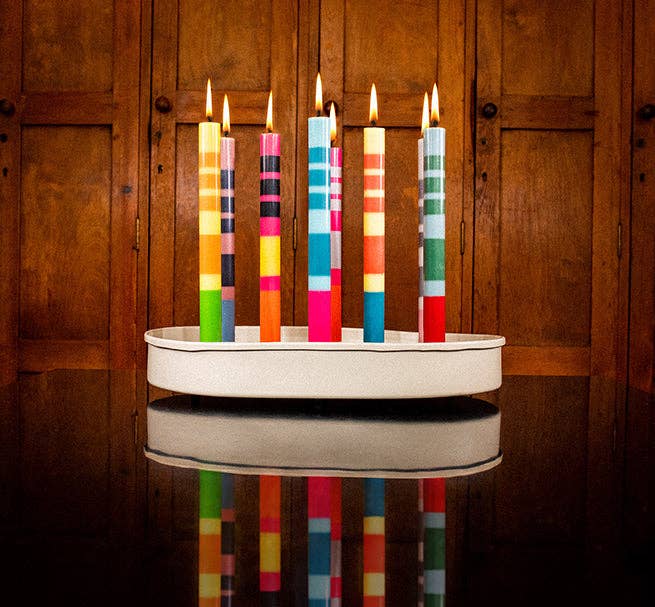 Colourful candles in a holder on a wooden surface