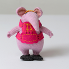 A knitted mouse figurine in light pink with a bright pink vest, yellow embroidered details, and dark gray shoes, shown against a plain light background.