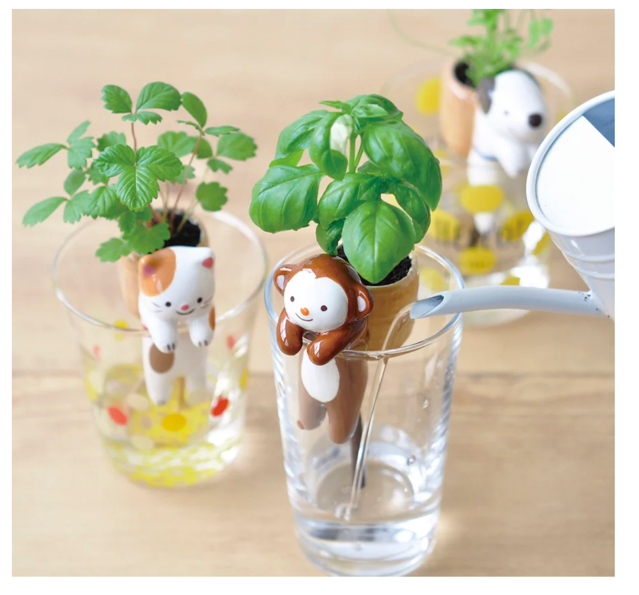 Three small animal-shaped planters with green plants inside on a wooden surface.