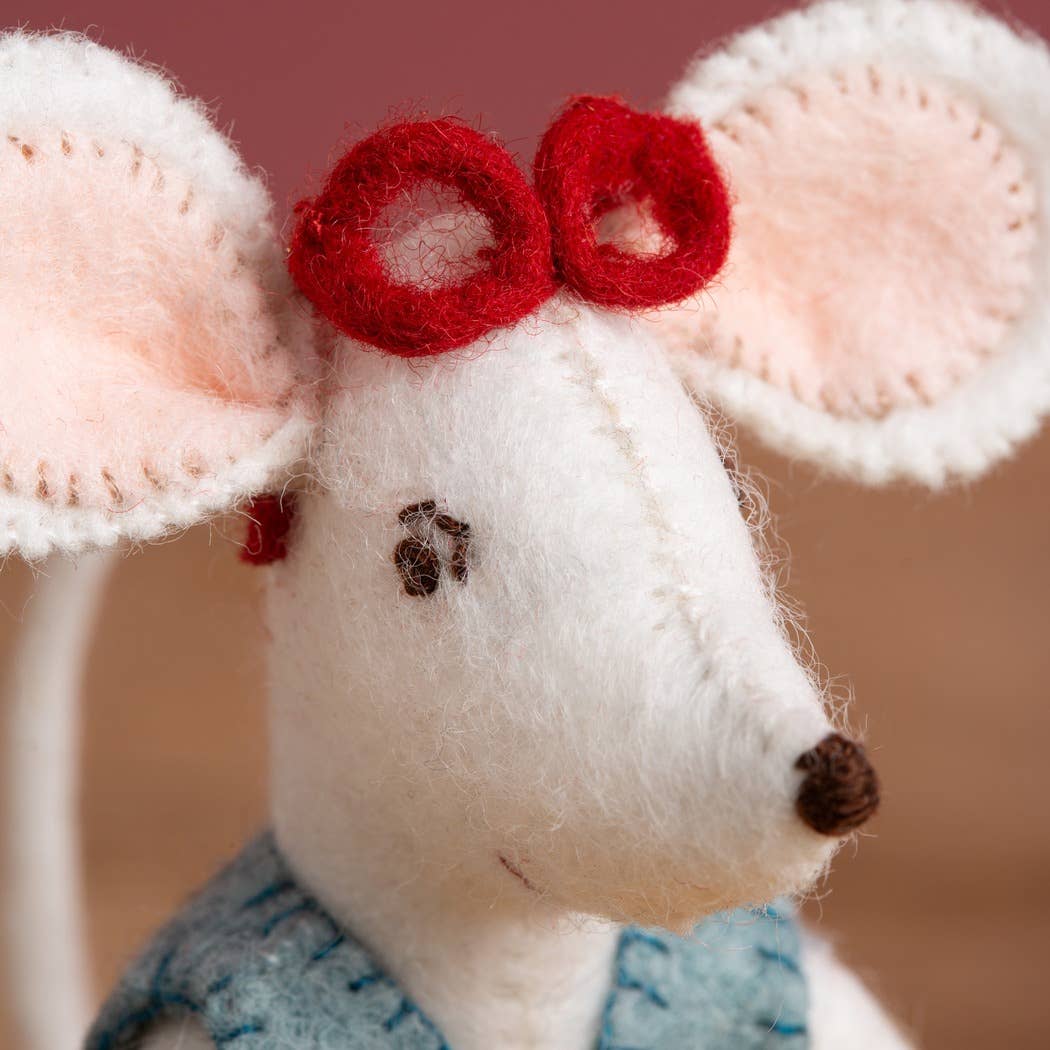 Close-up of a white mouse toy with pink ears and a red bow on a blurred background