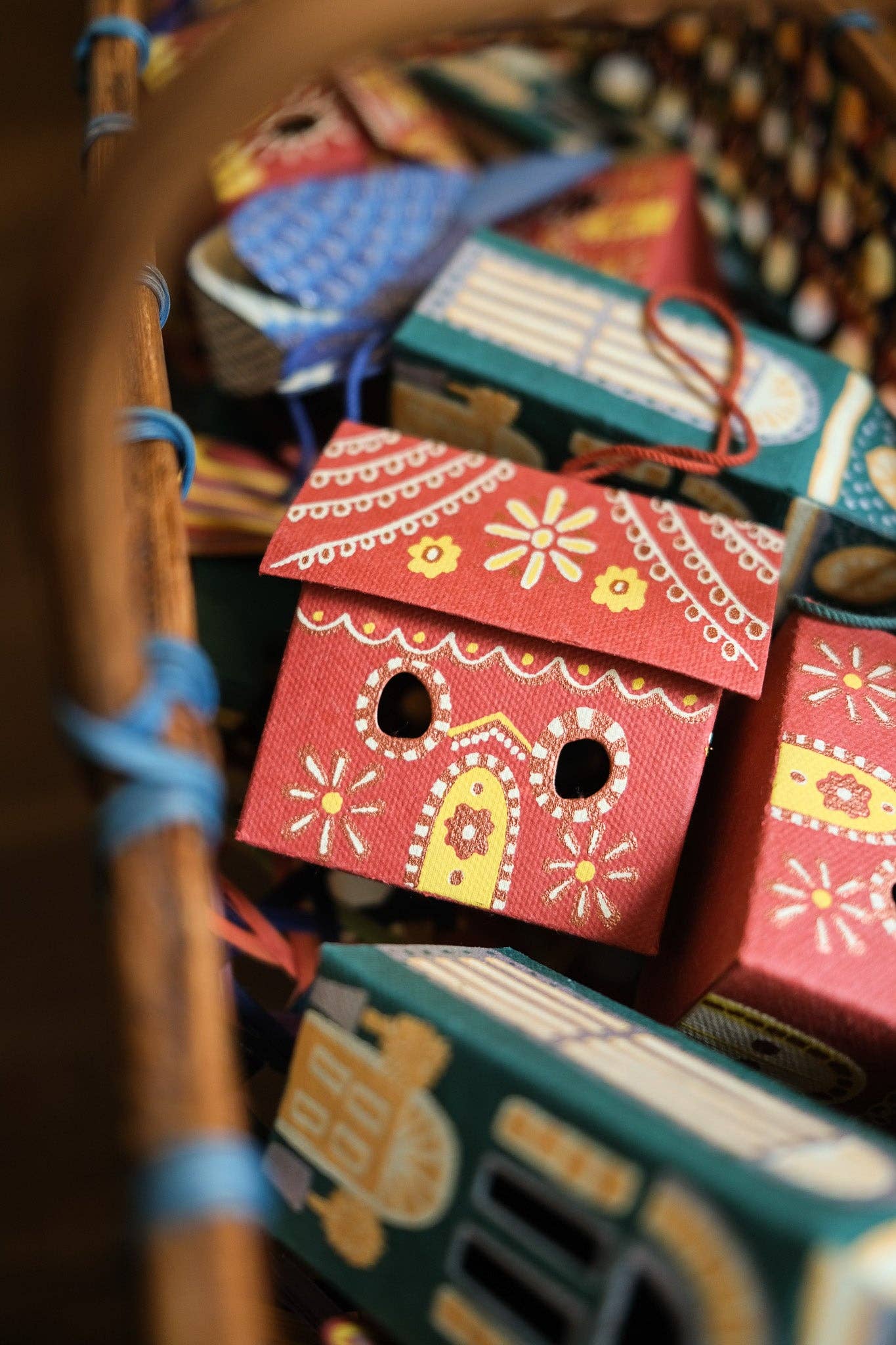 Colorful paper birdhouses with decorative patterns in a basket.