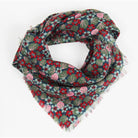 A fringed scarf with a dense floral pattern in red, pink, and green on a dark teal background, displayed on a clean white background.