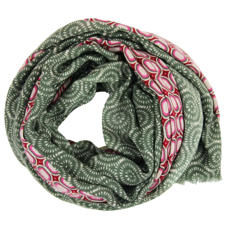 A lightweight infinity scarf with a green base featuring white circular mandala patterns and alternating pink and red geometric border stripes, displayed on a clean white background. 