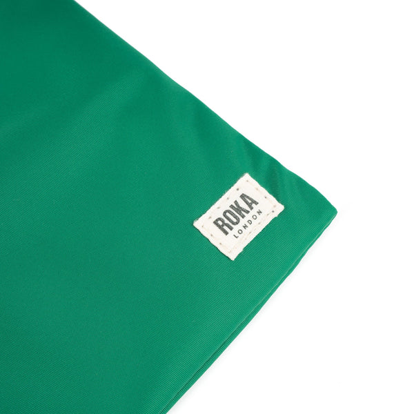 A close up photo of the bottom corner of an emerald green bag, showing the ROKA London label.