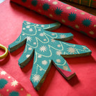 Stack of green paper cards with white patterns on a red surface with floral pattern