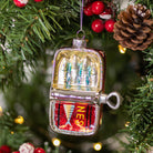 Decorative fishing lure ornament on a Christmas tree with lights and pine cones.