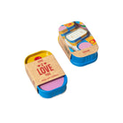 Two small candles in colorful tins with visible branding on a light green background