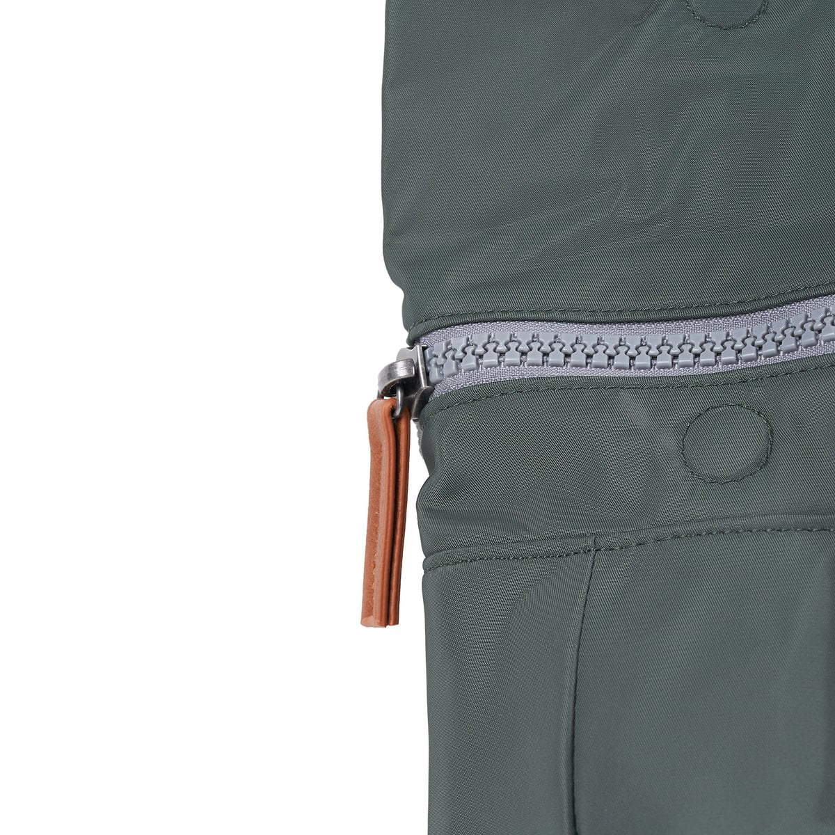 Close-up of a grey zip and brown pull tab on a green bag