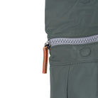 Close-up of a grey zip and brown pull tab on a green bag