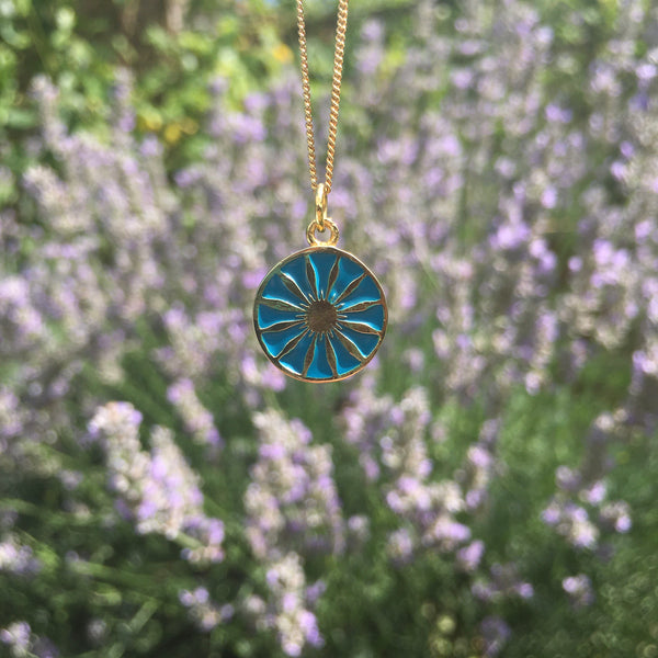turquoise daisy medallion in gold vermeil in front of lavender 